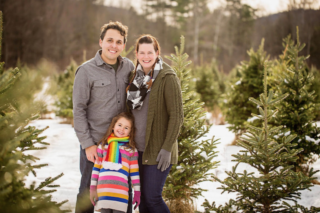 Scott, his daughter, and his wife standing in a snowy field for a family portrait